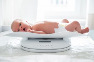 Newborn Girl In Diaper Lying On A Baby Scale