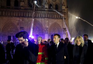 French President Emmanuel Macron, center, and his wife Brigitte walk away from Notre Dame cathedral in Paris, Monday, April 15, 2019. A catastrophic fire engulfed the upper reaches of Paris' soaring Notre Dame Cathedral as it was undergoing renovations Monday, threatening one of the greatest architectural treasures of the Western world as tourists and Parisians looked on aghast from the streets below.(Philippe Wojazer/Pool via AP)