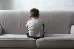 Little boy sitting on sofa at home. Child autism