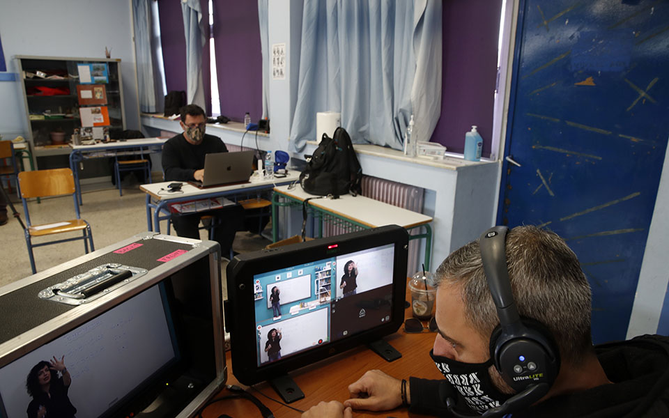A director watches the monitors as teacher Rania Koukli records lessons that are broadcast on public television, at an elementary school in Athens, Wednesday, Nov. 18, 2020. Most other European countries have vowed to keep schools open, but the pandemic has hit Greece hard for the first time in recent weeks following a successful lockdown in the spring, overwhelming hospitals in parts of the country. State television is making and broadcasting lessons, while teachers sit in empty classrooms talking to remote students. Despite some problems, they say it keeps children in touch with their schools. (AP Photo/Thanassis Stavrakis)