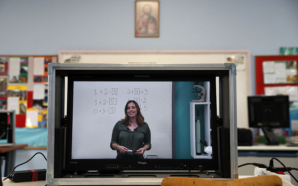 Teacher Sofia Klada is seen on a screen as she records lessons that are broadcast on public television, at an elementary school in Athens, Thursday, Nov. 19, 2020. Most other European countries have vowed to keep schools open, but the pandemic has hit Greece hard for the first time in recent weeks following a successful lockdown in the spring, overwhelming hospitals in parts of the country. State television is making and broadcasting lessons, while teachers sit in empty classrooms talking to remote students. Despite some problems, they say it keeps children in touch with their schools. (AP Photo/Thanassis Stavrakis)