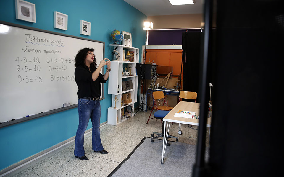 Teacher Rania Koukli records lessons that are broadcast on public television, at an elementary school in Athens, Wednesday, Nov. 18, 20202. Most other European countries have vowed to keep schools open, but the pandemic has hit Greece hard for the first time in recent weeks following a successful lockdown in the spring, overwhelming hospitals in parts of the country. State television is making and broadcasting lessons, while teachers sit in empty classrooms talking to remote students. Despite some problems, they say it keeps children in touch with their schools. (AP Photo/Thanassis Stavrakis)
