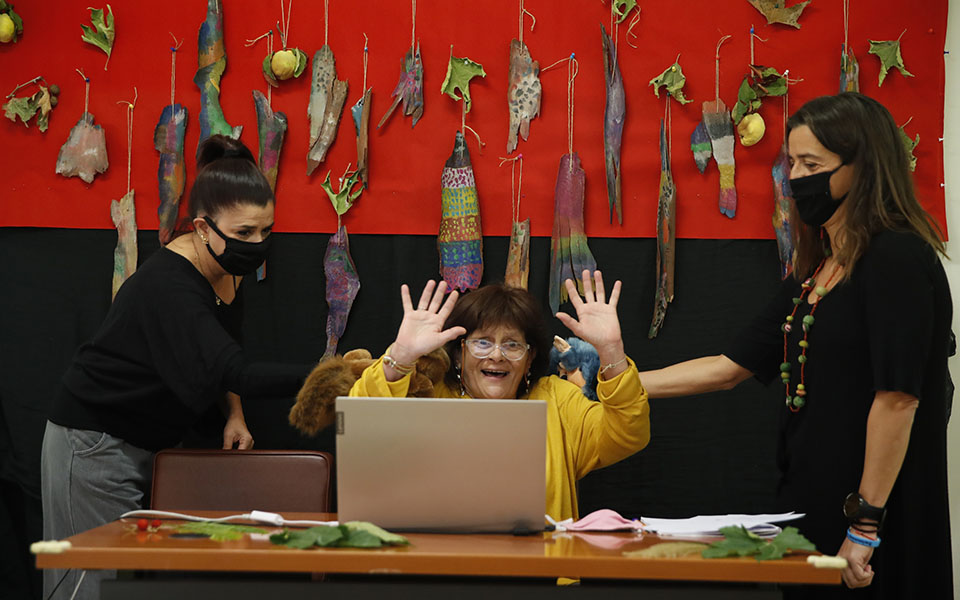 Ioanna Kabouri principal, center, raises her hands as teachers Aphrodite Tzevelekou, left, and Sofia Galiotou perform live an online puppet show for students at a kindergarten in Athens, Thursday, Nov. 19, 2020. Most other European countries have vowed to keep schools open, but the pandemic has hit Greece hard for the first time in recent weeks following a successful lockdown in the spring, overwhelming hospitals in parts of the country. State television is making and broadcasting lessons, while teachers sit in empty classrooms talking to remote students. Despite some problems, they say it keeps children in touch with their schools. (AP Photo/Thanassis Stavrakis)